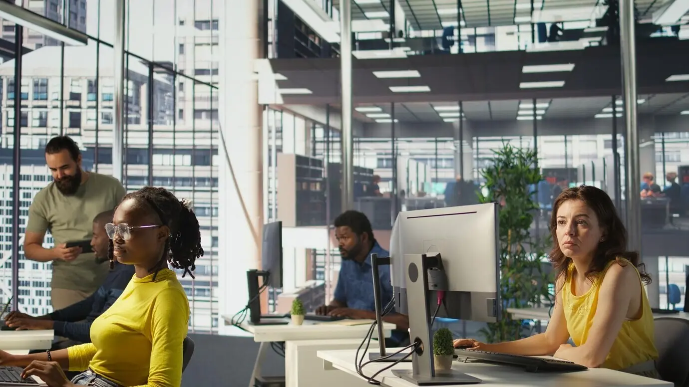 Trabajador sentado en un escritorio de oficina utilizando una computadora durante su turno de trabajo.