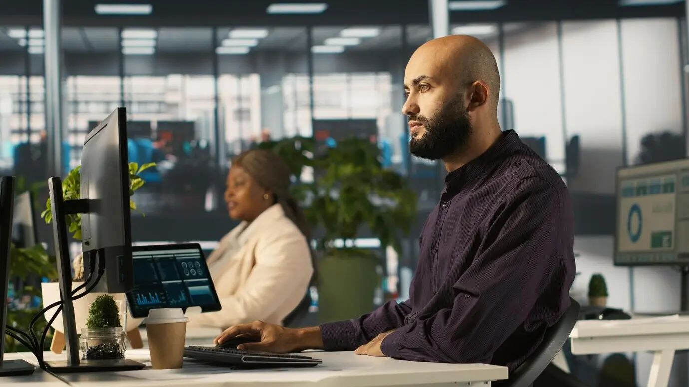 Hombre en una oficina revisa gráficos financieros y analiza KPIs.